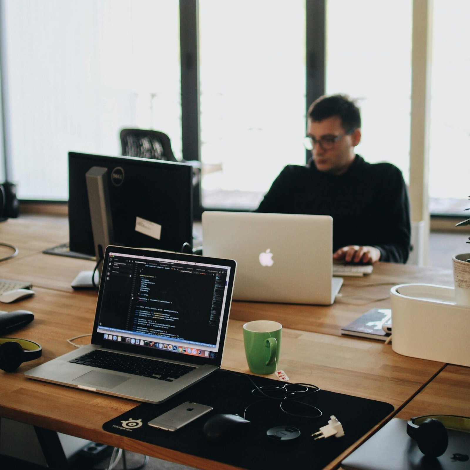 A web developer working on code in a modern office setting with multiple devices.